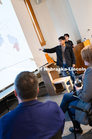 Andres Lucas, a fourth-year architecture student, gestures at a diagram of a murphy folding table sy