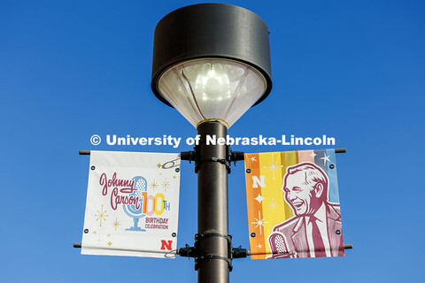 Signs celebrating University of Nebraska alum Johnny Carson’s 100th birthday hang from light poles