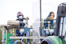 Brandi Sigmon and Christine Smith pours a packet of seeds into the hopper as the tractor slowly trav