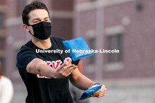 Kappa Kappa Psi’s Carson Scott throws a beanbag during the ASUN Cornhole Competition at the Cather
