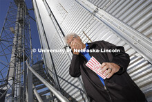 Husker alumnus Norm Krug enjoys a handful of Preferred Popcorn standing at the base of a grain bin o