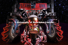 An “astronaut” holds a small corn plant with the Flex-Ro autonomous planter behind her. A plante