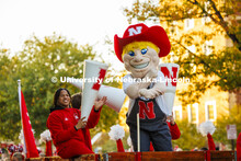 Herbie Husker and Amani Mfinanga cheer from a tractor-pulled wagon in the Homecoming parade. October