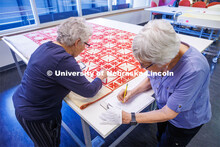 Volunteers Carolyn Kitterer (left) reads the names off the quilt while Susan Macy writes them down. 