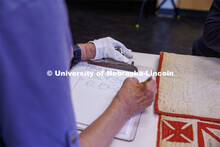 Volunteer Susan Macy (left) writes down the names off the quilt according to the column where they w