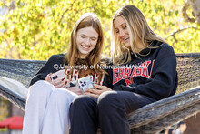 Freshmen Catherine Herold, left, and Elise Dehmlow laugh as they look on their phones while sitting 