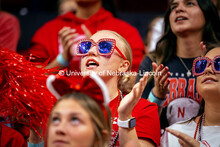 A student decked out in red rhinestone glasses celebrates at the Nebraska vs. Illinois Volleyball ga