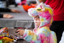 Small child dressed as a unicorn picks a piece of candy from a bowl. The University hosted a public 