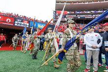 Members of the United States military carry their flags onto the field. Nebraska vs UCLA football ga