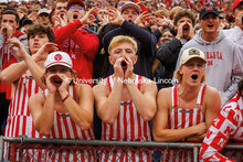 Fans in red and white striped overalls cheer in the student section at the Nebraska vs UCLA football