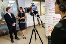 Damon Bennett, left, and Alaina Tomesh speak in front of the camera inside Andersen Hall. COJMC Elec