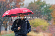 Tyler Kuzel uses an umbrella to repel the constant rain. Students walking in the rain on City Campus