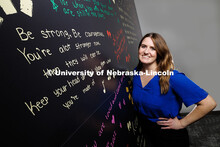 Gina May, Project SAFE clinical coordinator and graduate student, stands next to a wall containing i