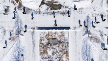 Aerial view of students crossing campus in the snow. Students cast shadows on the snow covered sidew