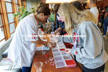 Paige, an incoming freshman, grabs beads to make a Husker-themed friendship bracelet at the Tailgate