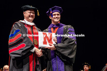 (Left) Robert Schafer, a chairman on UNL’s Board of Regents, hands his son, Nolan Schafer his law 