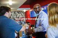Chancellor Rodney D. Bennett hands a cup of coffee to Cayden Chapman (left), a Business Graduate Stu