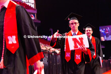 Cole Miller points at his diploma as he walks down the aisle at Pinnacle Bank Arena. Miller is a gra