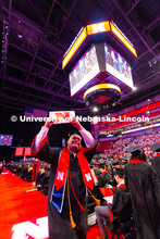 Business Administration graduate Corey Nguyen holds up his degree to friends and family seated in th