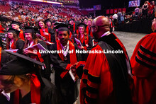 Chancellor Rodney D. Bennett shakes hands with a graduate leaving Pinnacle Bank Arena after the Univ