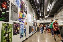 Visitors walk past a wall of projects from Professor, Jesse Fleming’s, Visual Expression Studio du