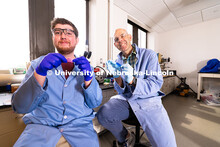 Stephen Morin, Associate Professor of Chemistry, and doctoral student Brennan Watts hold two colorfu