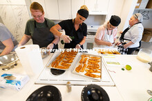 Kelly Whitney and Dusty Stevens prepare baking sheets of whitefish fillets coated with a blackened s