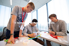 Kenneth Miller leans over Brooks Xia and Kameron Bailey as the trio work on constructing a bridge ou