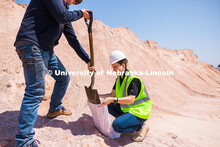 Jake Venne, lab technician for Barkley Asphalt, scoops aggregate gravel into a sample bag for Taisa 