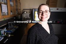 Erin Carr poses in front of vials filled with cyanobacteria, algae and fungus and equipment in her l