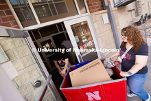 Sophia Bretz, a junior studying actuarial science, maneuvers a cart through a doorway in The Village