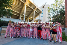 Husker students wear bibs and pose for a group photo outside of Memorial Stadium before the football