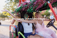 Members of the Alpha Xi Delta sorority wave to spectators as they drive their decorated golf cart to