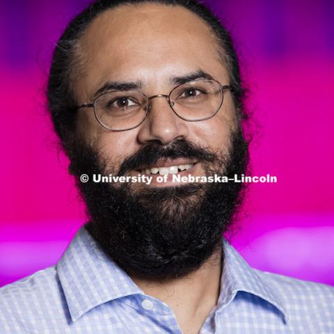 Harkamal Walia checks the progress of a rice plant growing in the Lemna Tech High Throughput Phenotyping facility at the Greenhouse Innovation Center on Nebraska Innovation Campus. The magenta glow is caused by custom LED grow lights. The facility is an automated system which moves the plants via conveyor belts and automatically waters them and then records their growth daily.  August 11, 2015.  Photo by Craig Chandler/University Communications