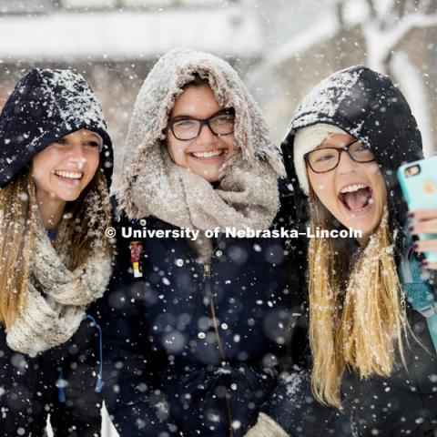 Kayla Felix, left, and Alli Hauger smile as Emily Hames takes a selfie of them while they walked to class during the hardest snow. A snow storm of large wet flakes falls on UNL Monday, January 25 2016. Photo by Craig Chandler / University Communications