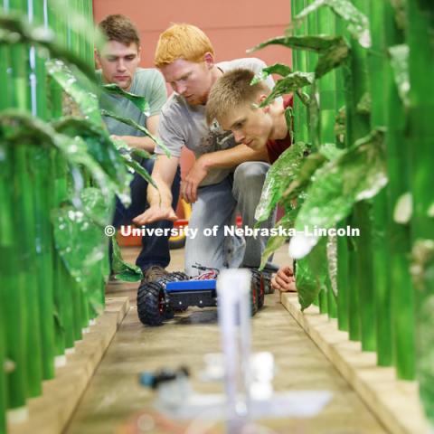 Ethan Nutter, graduate student in mechanized systems management discusses a robotic vehicle which is being developed to count seedlings in a corn row to measure germination. Tyler Troyer, graduate student in BSE, is at left and Lukas Renker, senior in Mechanical Engineering, is at right. Robotics lab on east campus. Biological Systems Engineering. August 15, 2016. Photo by Craig Chandler / University Communication.