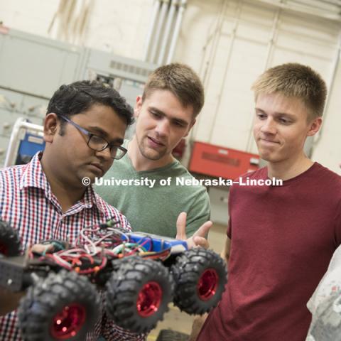 Santosh Pitla discusses the electronics on a robotic cart with Tyler Troyer, graduate student in BSE, Ethan Nutter, graduate student in mechanized systems management, and Lukas Renker, senior in Mechanical Engineering. Robotics lab on east campus. Biological Systems Engineering. August 15, 2016. Photo by Craig Chandler / University Communication.