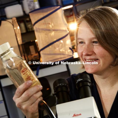 Kristi Montooth holds a jar of genetically marked fruit flies. The flies are raised in old glass milk bottles, an unusual recycling option. Montooth, Associate Professor of Biology, has published an article about molecular evolution and ethanol tolerance