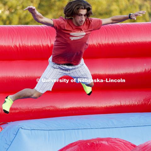 Kyle Jamison takes to the air as he tries to complete the Leaps and Bounds, an obstacle course comprised of three inflated balls in an inflatable pit. Back to School Bash on the Nebraska Union Plaza and Green Space sponsored by Campus NightLife. Students