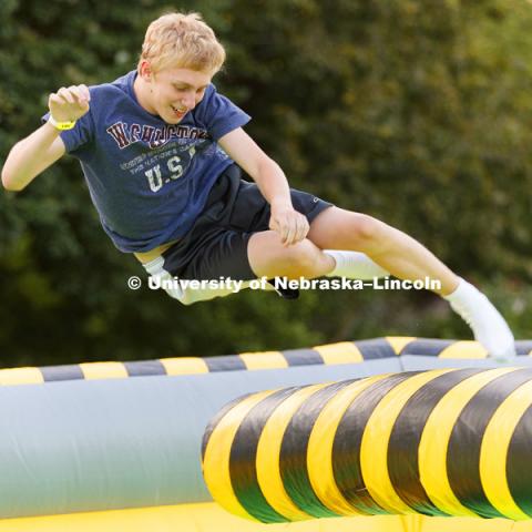 Cameron Hosler leaps over a revolving column as he tries to beat the spinning Meltdown inflatable. Back to School Bash on the Nebraska Union Plaza and Green Space sponsored by Campus NightLife. Students enjoyed a headphone disco party, inflatable games,