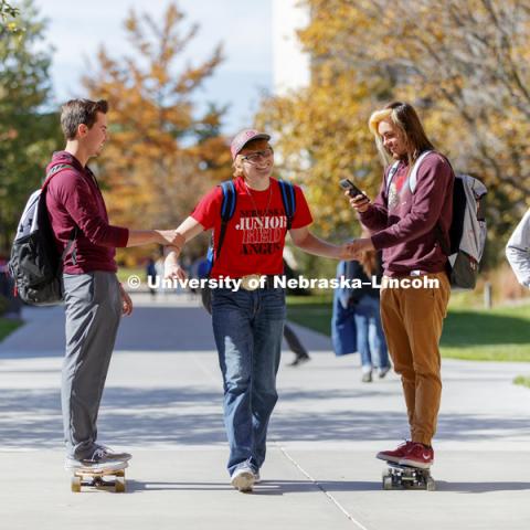 Ryan Melanson, left, and Edward Sierra-Lee are powered by Garrett Brentlinger as the three walk and roll in between classes Wednesday. City Campus fall day. October 25, 2017. Photo by Craig Chandler / University Communication.