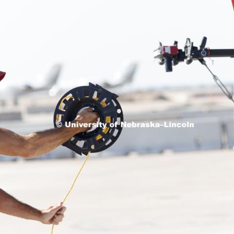 Jim Holloway unwinds Ethernet cable to connect the high speed camera set to record the crash test to computers in their trailer. Test of bull-nose barrier for use in medians to protect cars from overpass columns. Test was at university's Midwest Roadside Safety Facility at the Lincoln airport. June 5, 2018. Photo by Craig Chandler / University Communication.