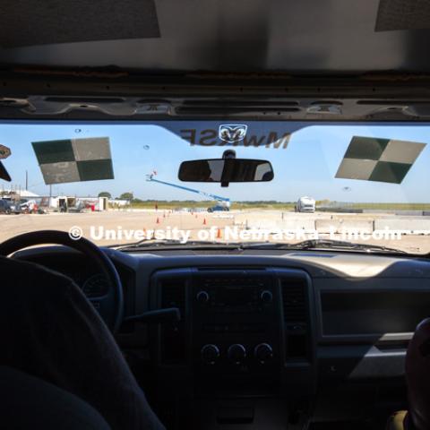 Logan Jacobsen, sophomore in mechanical engineering major, shares the front seats with a crash test dummy during a slow speed check of the steering cable. Jacobsen was "driving" to operate the brakes during the non-crash part of the test. Test of bull-nose barrier for use in medians to protect cars from overpass columns. Test was at university's Midwest Roadside Safety Facility at the Lincoln airport. June 5, 2018. Photo by Craig Chandler / University Communication.