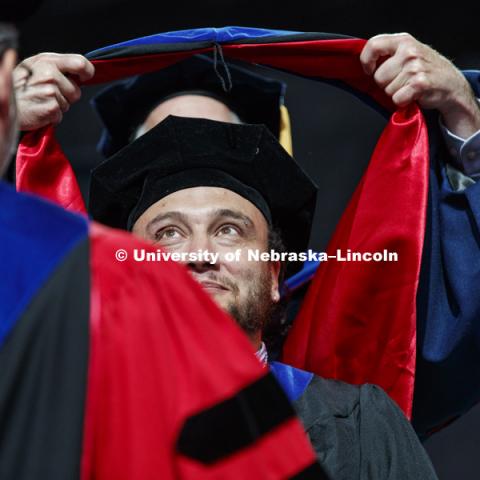 Jose Monroy has his eye on the prize as his doctoral hood is draped over his head. Summer Commencement at Pinnacle Bank Arena. August 11, 2018. Photo by Craig Chandler / University Communication.