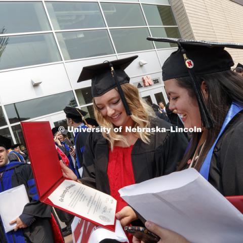 Allison Winter and Ariel Medrano admire each others diplomas following Summer Commencement at Pinnacle Bank Arena. August 11, 2018. Photo by Craig Chandler / University Communication.