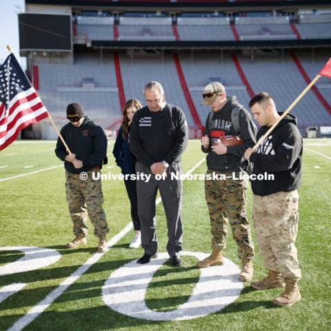 Jerod Post, '13 and a Marine veteran, undergraduate Natalie Kraft, a Navy veteran, Athletic Director Bill Moos, undergraduate and Marine veteran Jake Post and undergraduate and Army veteran Jared Collins observe a moment of silence prior to the starting point of the Ruck March. Beginning of veterans Ruck March, which uses Nebraska and Iowa veterans to carry the game ball from Lincoln to Iowa City. November 14, 2018. Photo by Craig Chandler / University Communication.