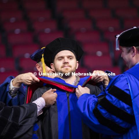 John Evans, Phd in Biological Engineering, has his doctoral hood placed over his head by Professors Santosh Pitla and Joe Luck at the Graduate Commencement and Hooding in Pinnacle Bank Arena. December 14, 2018. Photo by Craig Chandler / University Communication.