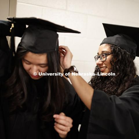 Xiao Yun Sim has her mortarboard pinned on by Chandni Manoj before the ceremony. Undergraduate Commencement in Pinnacle Bank Arena. December 15, 2018. Photo by Craig Chandler / University Communication.