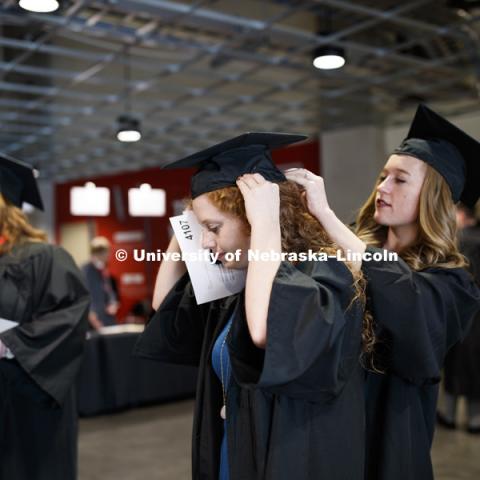 Morgan Thomsen has her mortarboard pinned on by Delaney McFadden before the ceremony. Undergraduate Commencement in Pinnacle Bank Arena. December 15, 2018. Photo by Craig Chandler / University Communication.