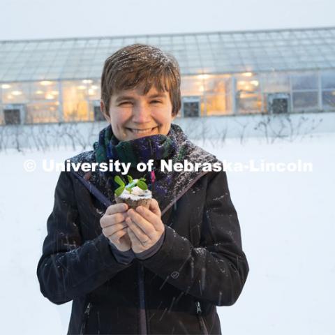 Rebecca Roston, assistant professor of biochemistry, holds a pea plant outside the Beadle Hall greenhouses. Roston, who recently earned a National Science Foundation CAREER award, is studying how more than 30 species of plants respond to freezing. February 19, 2019. Photo by Craig Chandler / University Communication.